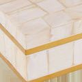 Close-up showing pale geometric mother-of-pearl tiles and smooth warm brass trim detail