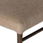 Close-up of the corner of the cushioned seat with beige fabric and oak leg