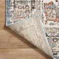 Rug corner lifted to expose tightly woven light beige backside on wooden floor