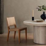 Villa Dining Chair shown next to round light wood dining table with plates, candle, and black vase
