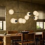Chandelier lit over rustic wooden dining table with leather chairs, bowls of fruit, and warm wall tones