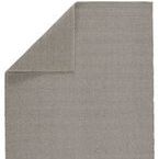 Gray rug corner flipped over revealing reverse side with similar striped weave pattern