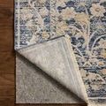 Corner of rug lifted up to show backing and thickness on wooden floor