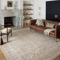 Rug styled in living room with brown leather sofa, marble fireplace, and decorative shelving.