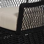 Close-up detail of woven rattan rope wrapping chair arm and beige cushion fabric texture