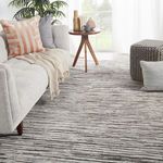 Rug styled in a modern living room setting with light gray sofa, wooden side table, and neutral decor