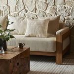 Danza Outdoor Pillow styled on beige sofa in rustic stone-wall living room