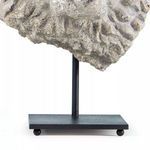 Close-up of black metal stand base with round feet holding grey lion head sculpture