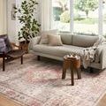 Rug laid in living room with cream sofa, brown leather chair, and large window lighting