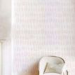 Wallpaper installed on wall with white armchair and pillow in softly lit room with wood flooring