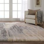 Side view of rug under chair with beige cushions and gray throw highlighting pile height