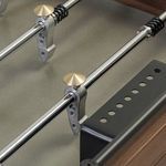 Close-up of foosball rods with round metallic bronze score counters and detailed cast aluminum players
