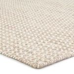 Beige and ivory 100% wool Pompano dhurrie rug with small-scale circular lattice pattern and flat weave texture