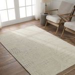 Karim rug displayed in modern room setting with wood floor, natural light, and beige armchairs