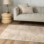 Rug styled in a living room setting under a light gray sofa with beige pillows and wooden floor