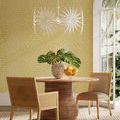 Bismarkia chandelier lit, hanging over round wooden dining table with four chairs in yellow-patterned room