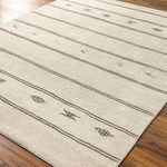 Rivi Rug shown at an angle on wood floor highlighting flat medium pile and Bohemian Global patterns