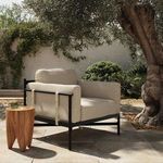 Hearst Outdoor Chair positioned on outdoor stone patio under tree with wooden side table nearby