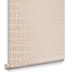 close-up of rolled wallpaper showing rose gold hexagon pattern on blush textured paper