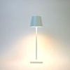 White modern table lamp with a slim metal frame and a tapered shade emitting soft white light