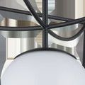 Close-up of black metal rods converging above the milky white globe in the Rochefort lantern