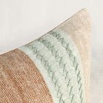 Extreme close-up of knitted stripe detail in soft green on corner of pillow