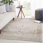 Tajsa Medallion Gray Gold Rug styled in bright living room with sofa, side table, and pouf