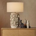 Lamp, ceramic cat figure, and two vases styled on top of chest against beige textured wall