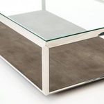 Close-up angled view of glass top edge and steel frame meeting the brown textured base