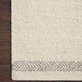 Close-up of rug corner on dark wood floor highlighting plush texture and silver chevron border