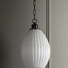 Side angle view of pendant light showing glossy fluted white glass shade and dark bronze fixture