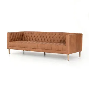 Tufted camel-colored leather sofa with squared arms, button detailing, and light wood legs