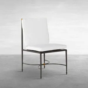 Outdoor side chair with white cushions and wrought aluminum frame featuring subtle gold accents on finials