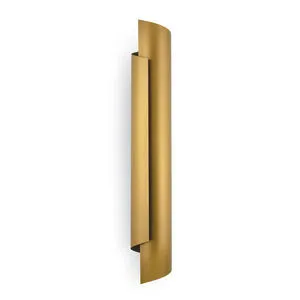 Tall natural brass sconce with wrapped steel design featuring smooth curving panels and a warm golden finish