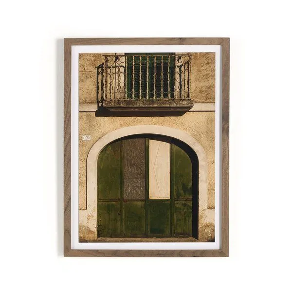 Framed photograph of vintage rustic green and white arched door with ornate balcony above, in a beige textured wall