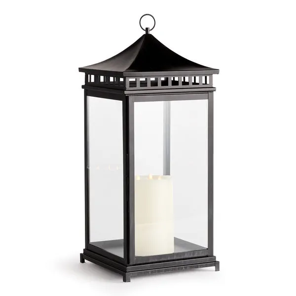 Tall black outdoor lantern with wide sweeping top and clear glass panes showing a white candle inside