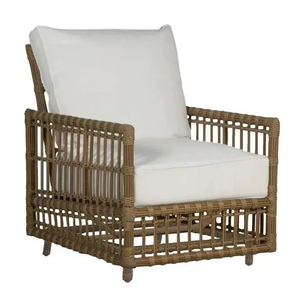 Outdoor accent lounge chair with woven tan rattan frame and white cushions