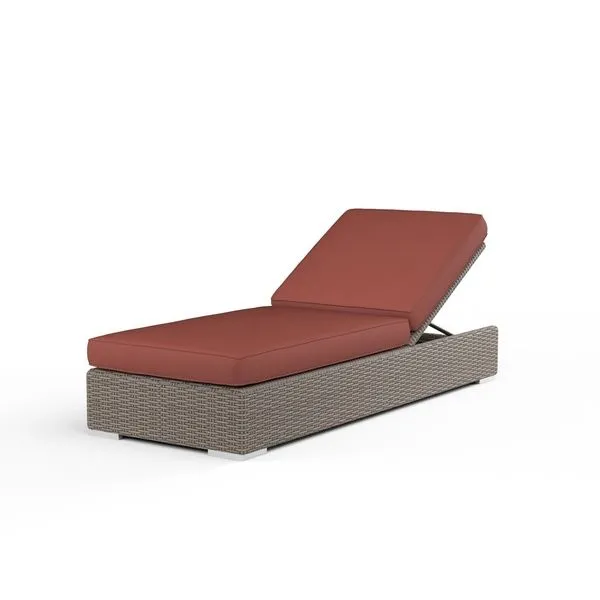 Adjustable outdoor chaise with driftwood resin wicker frame and rust-colored plush cushions in reclined position