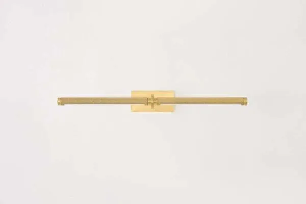 Slim modernist brass picture light with knurled texture along the shade and a rectangular wall mount