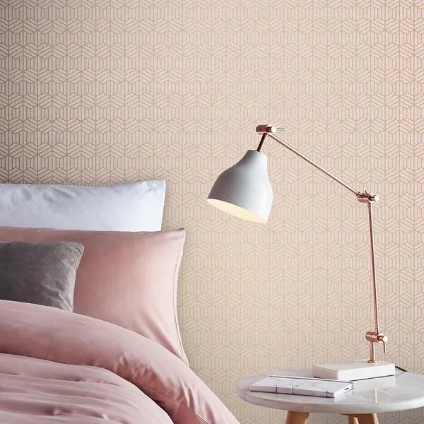 blush textured wallpaper with rose gold hexagon pattern styled in soft pink bedroom setting with white pillow and modern lamp