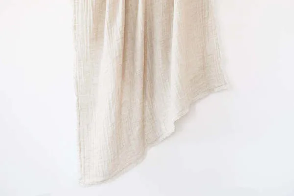 Light beige crinkled double weave linen throw with a soft textured surface and raw edges