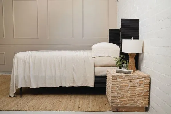 Set of two natural bamboo and linen pillowcases in warm neutral tone with subtle frayed edges on a black bed frame in a mi...
