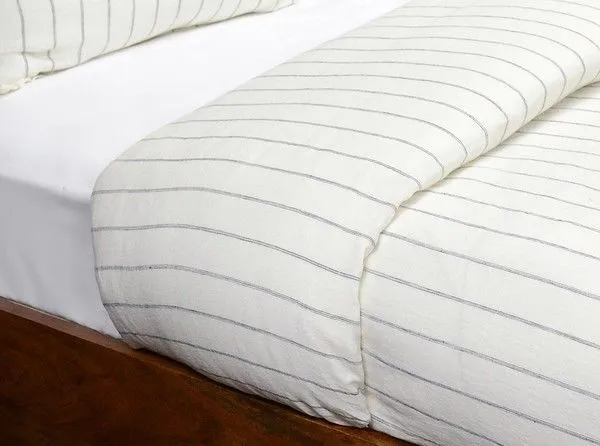 Ivory linen duvet with woven pinstripe design on a wooden bed frame, showing smooth texture and light stonewash finish