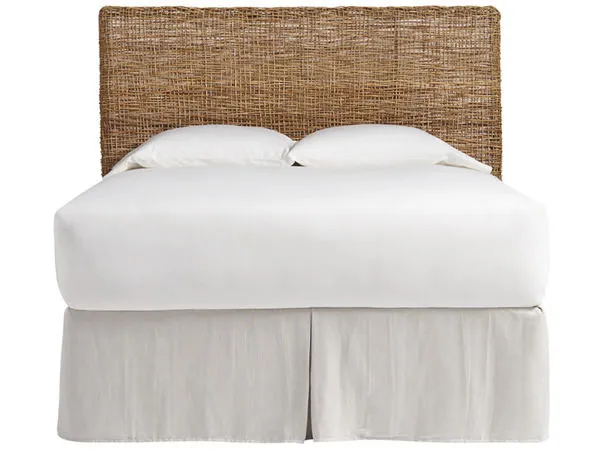 Rustically woven wicker Escape Nesting Headboard with warm brown tones behind white bedding