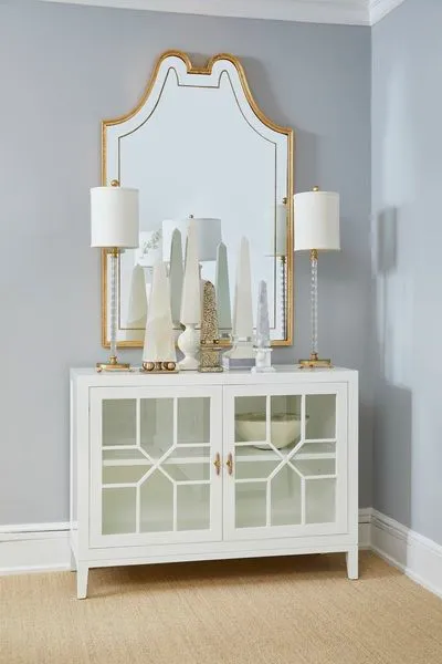 White Neoclassical ceramic obelisk sculpture with intricate carved details and glossy glaze on a white sideboard