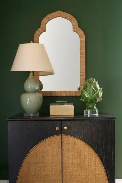 Small natural raffia Pisco Box with clear acrylic lid and champagne gold handle on dark wood cabinet with green walls