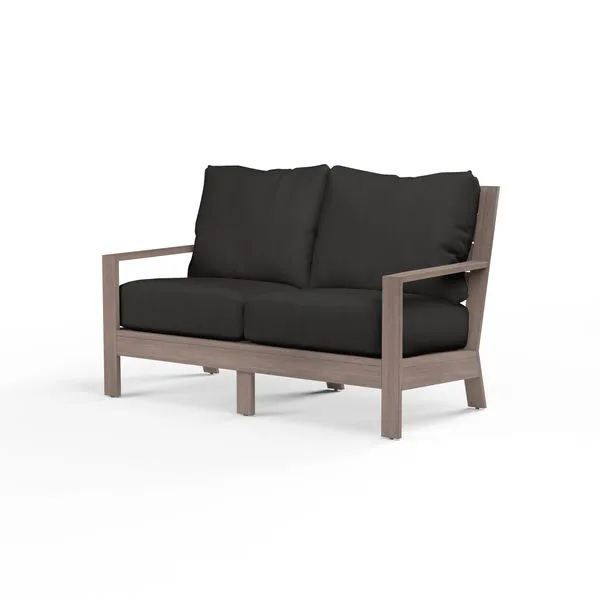 Laguna Loveseat outdoor sofa with hand-brushed aluminum frame mimicking driftwood and black seat and back cushions