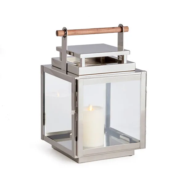 Adwin outdoor lantern with polished chrome frame, wide glass panes, and natural teak handle holding white pillar candle