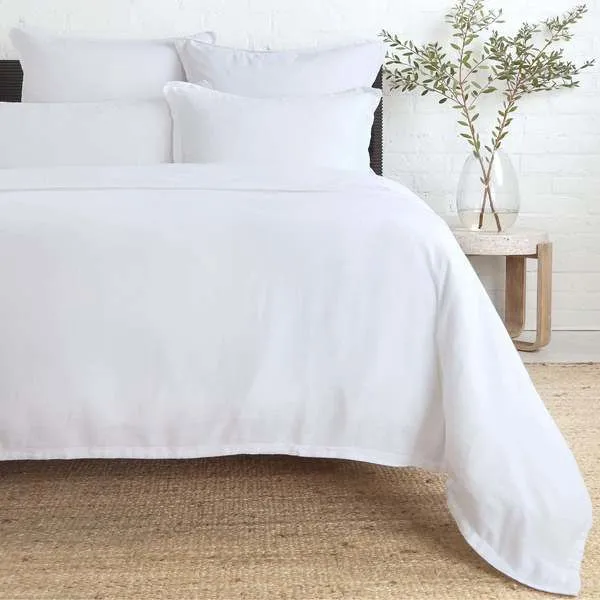 White Georgie Bamboo Linen Duvet on bed with soft, smooth drape over natural fiber rug and simple bedside table