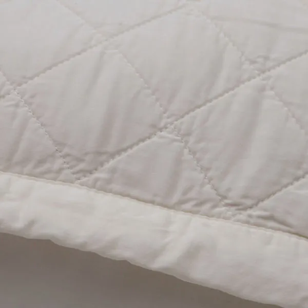 Close-up of Monaco Coverlet fabric showing smooth bamboo sateen texture and quilted diamond stitching detail
